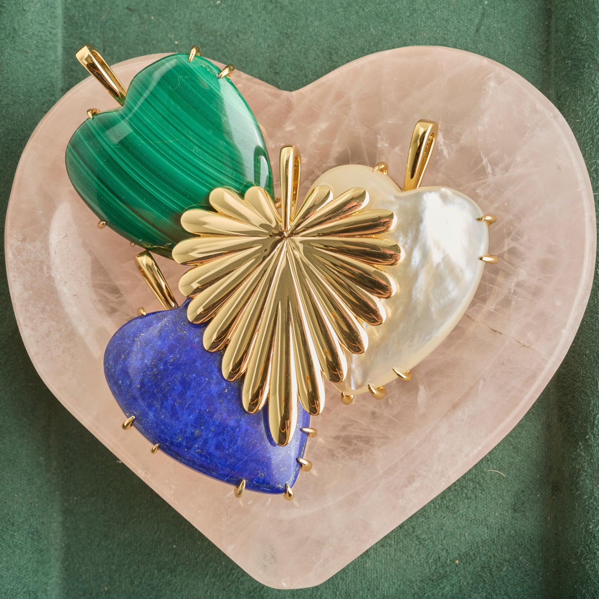 A gold heart pendant, green malachite pendant, white mother of pearl, pendant, and a lapis heart