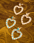 Stylized shot of the love in the sun earrings in turquoise and mother of pearl on marbled brown background