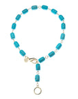 Necklace features chunky turquoise beads with oversize gold lobster clasp and ring to attach pendants. Shown as a lariat.