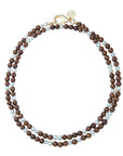 Double wrap beaded necklace features round wooden beads with pearl bead interspersed throughout. Necklace has oversized gold lobster clasp