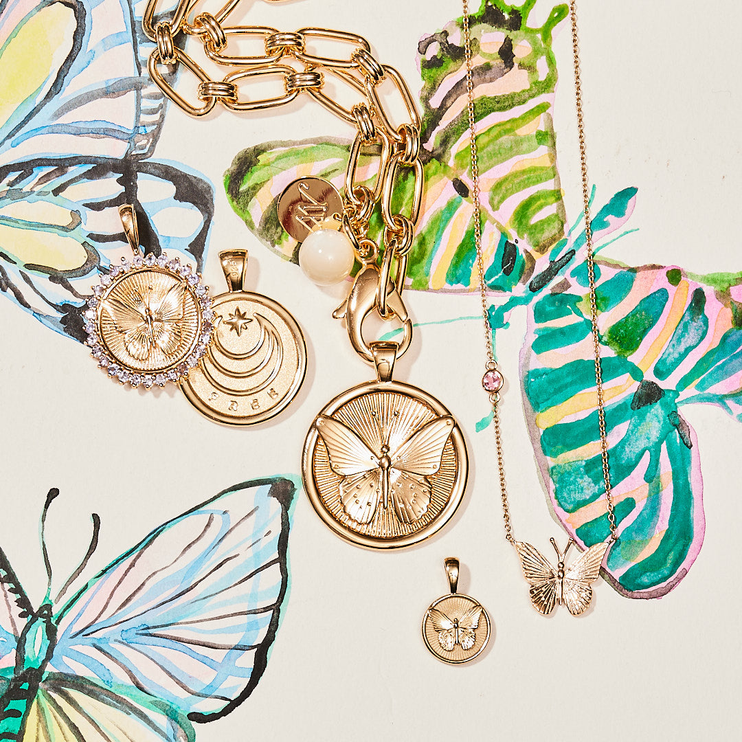 Stylized laydown image of gold Butterfly coin pendants with sketch of design