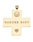 Back of gold Greek cross pendant features moon and star logo, heart icon, and the phrase GARDEZ BIEN