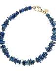 Beaded necklace with irregular shaped lapis stones with small round gold beads interspersed, also features oversized gold lobster clasp