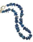 Beaded necklace with irregular shaped lapis stones with small round gold beads interspersed, also features oversized gold lobster clasp