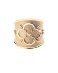 Gold cigar band ring with quatrefoil design featuring arrows and a heart