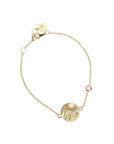 Gold chain bracelet featuring mini coin with illustration of the sun, waves, and a heart with pink tourmaline accent on chain