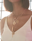 Model wearing layered gold necklaces