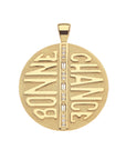 Gold coin pendant features row of white topaz stones down the center and the french phrase BONNE CHANCE