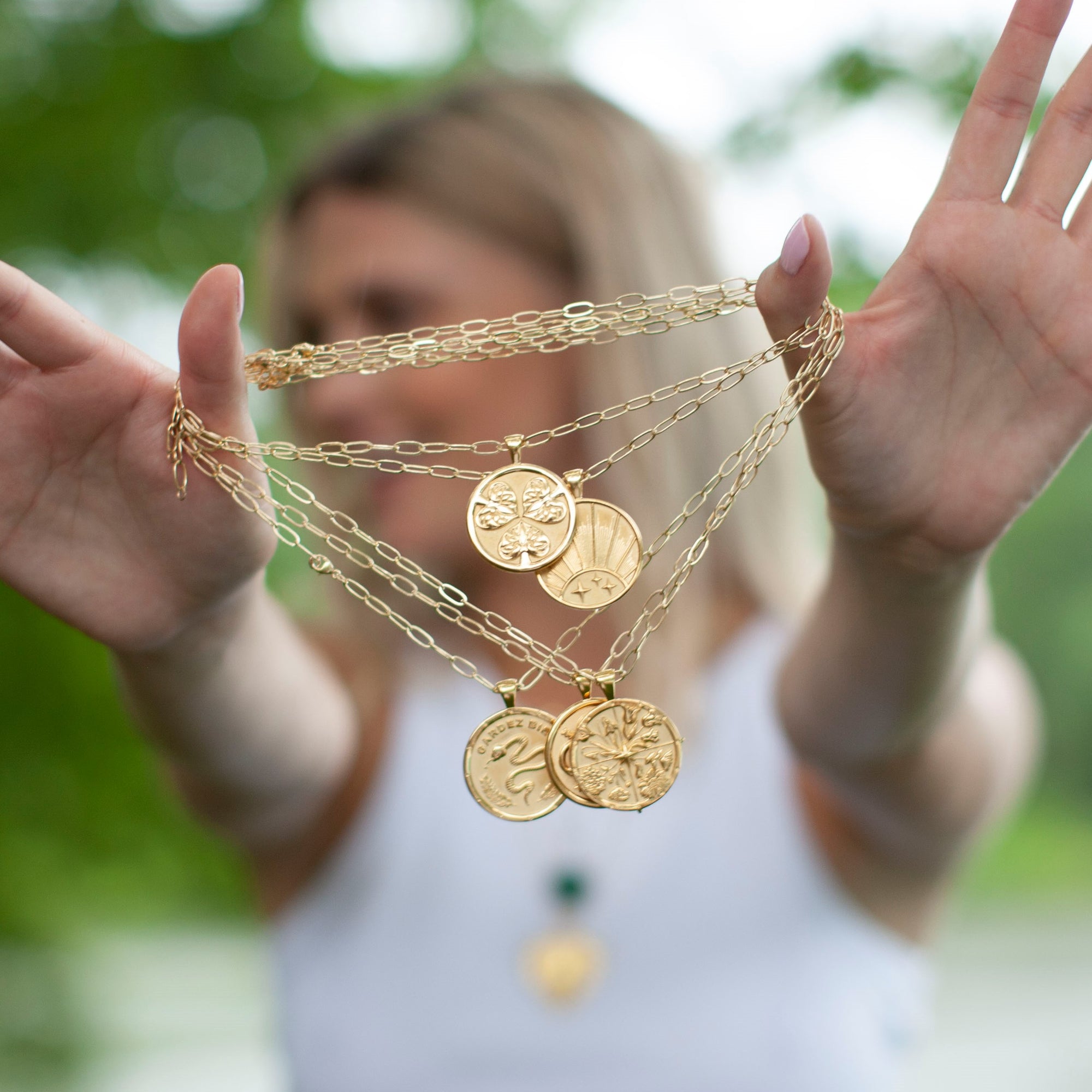 Model holding out coin necklaces
