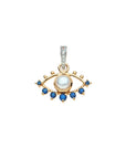 Gold cutout evil eye pendant features mother of pearl cabochon in the center and blue sapphire accents along the edge. Feature white topaz stones on the bail