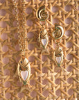 Stylized shot of strong amore fish pendant and strong amore fish earrings on rattan surface