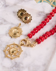 Stylized shot of sun pendants, sun earrings, and coral beaded necklace on a marble tray