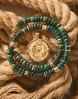 Stylized shot of the malachite gumdrop necklace and the strong circling koi coin pendant on a background of twisted ropes
