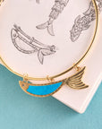 Stylized shot of the keep swimming fish in turquoise on top of a sketch of the design