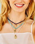 Model wearing the strong in the waves necklace, strong keep swimming necklace, and protect eye on your heart necklace