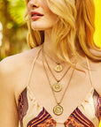 Model wearing various gratitude coin pendants layered on gold chains
