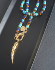 Stylized shot of the protect ancient eye tusk pendant on the shoreline mix gumdrop beaded necklace.