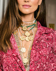 Model wearing assorted gold coin pendants and chains
