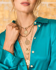 Model wearing various gold chains and gratitude pendants