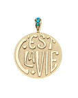 Gold coin pendant features the phrase "C'EST LA VIE", heart and star accents, and turquoise stones on the bail