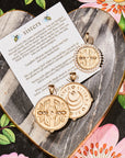Stylized laydown image of three gold coin pendants with card and meaning