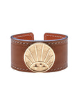 Brown leather cuff bracelet featuring gold coin with rising sun design