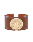 Brown leather cuff bracelet featuring gold coin with rising sun design