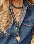 Model wearing assorted beaded necklaces and coin pendants