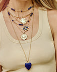 Model wearing various gold and lapis chains and pendants