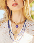 Model wearing the protect traveling eye, protect cutout coin, gold chains, and lapis double wrap
