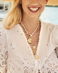 Model wearing layered shell pendants and coins