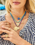 Model wearing assorted evil eye pendants and evil eye rings