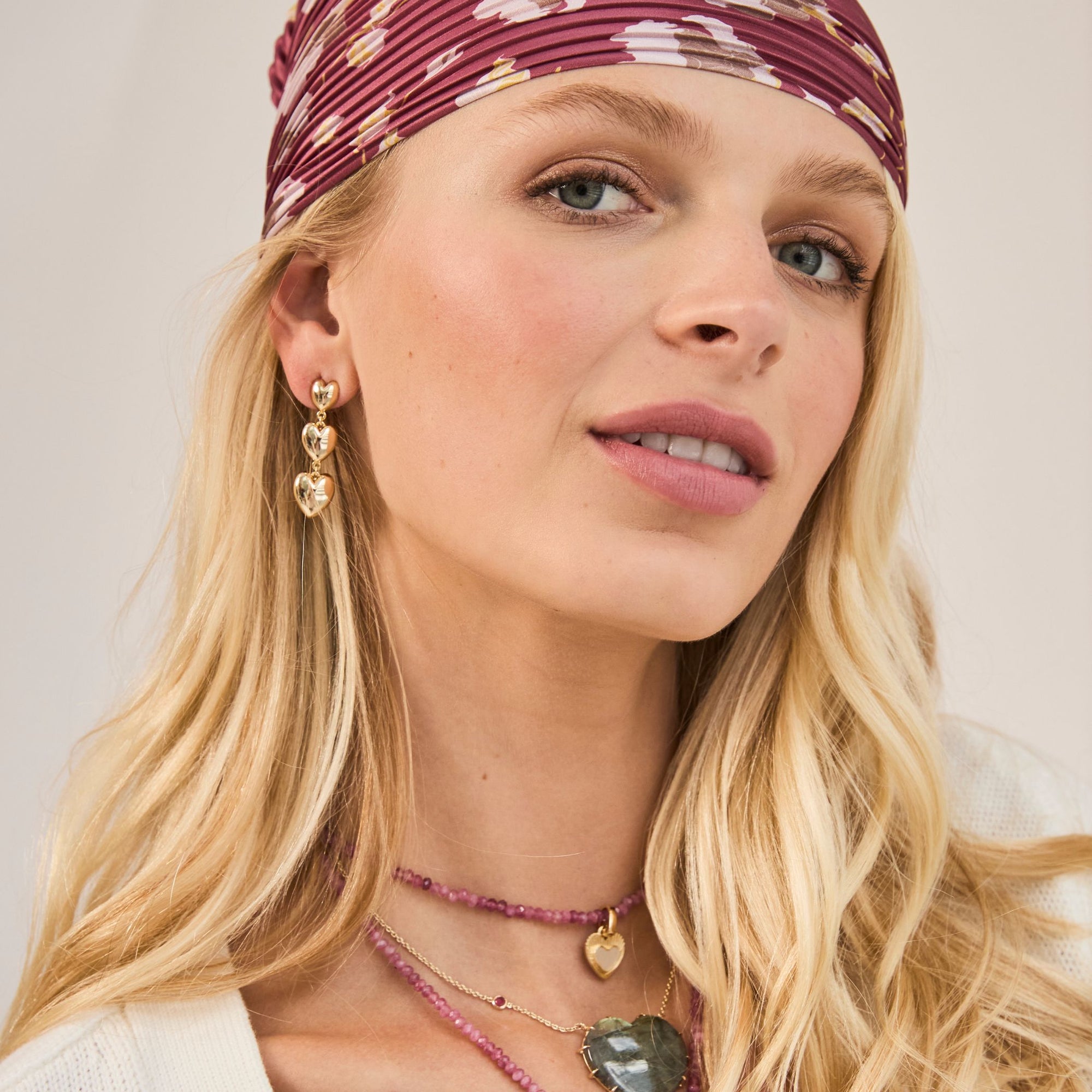 Model wearing gold heart drop earrings