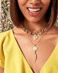 Model layering gold tusk with other necklaces