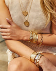 Model wearing stacks of gold cuffs