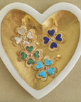 Stylized shot of 4 different clover pendants in gold heart dish