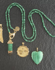 Stylized shot of lucky feather pendant, eagle coin, malachite sun ray, malachite heart, and malachite beaded chain