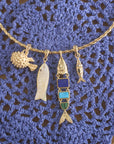 Stylized shot of various fish pendants on the twisted neck cuff laid out on blue crochet background