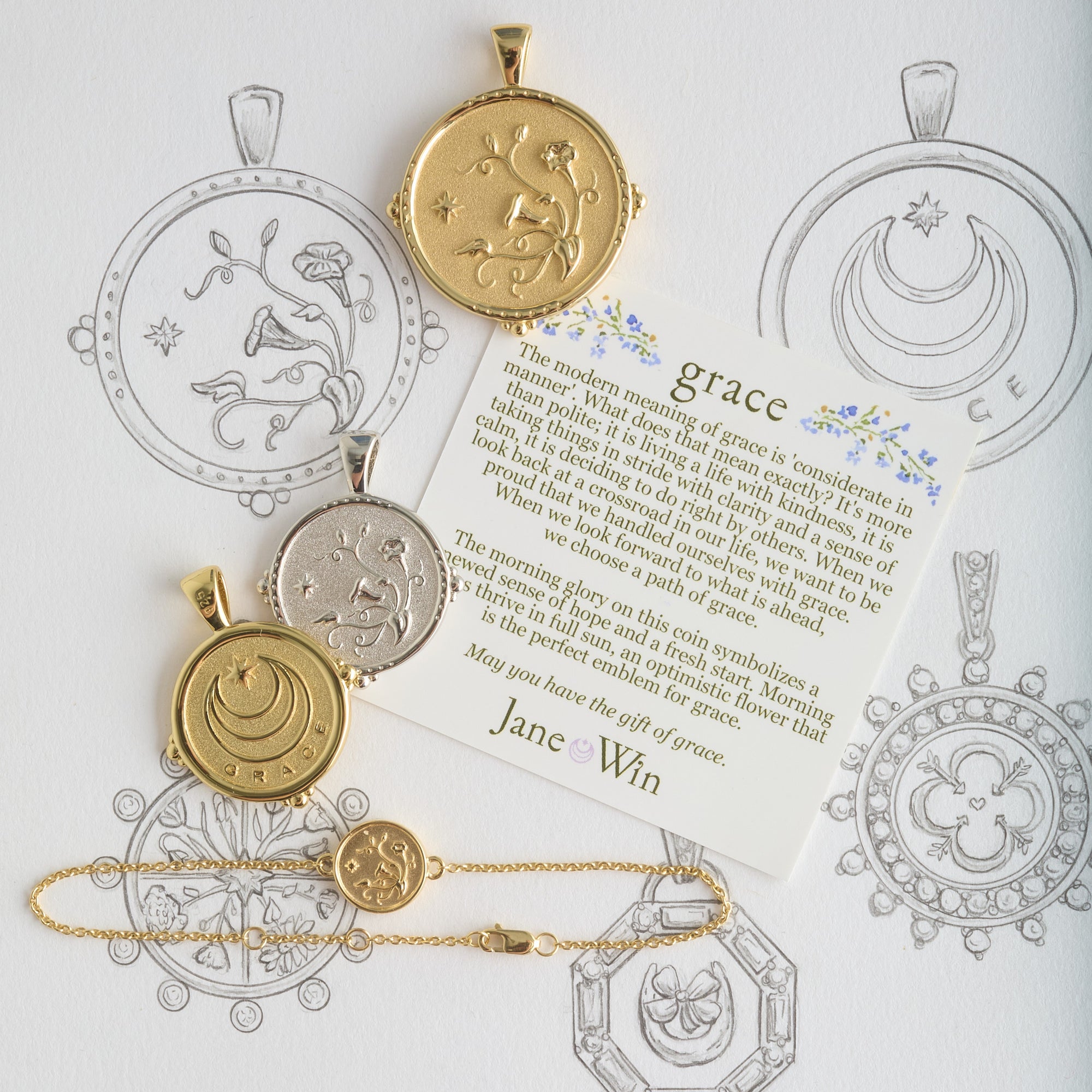 Stylized shot featuring various grace coins and bracelet with grace card on sketches of the grace coin design