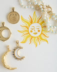 Stylized shot of moon pendants and pearl necklace with watercolor sun painting