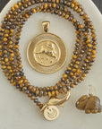 Stylized shot of gold rabbit coin, tigers eye beaded chain, and carved tigers eye rabbit