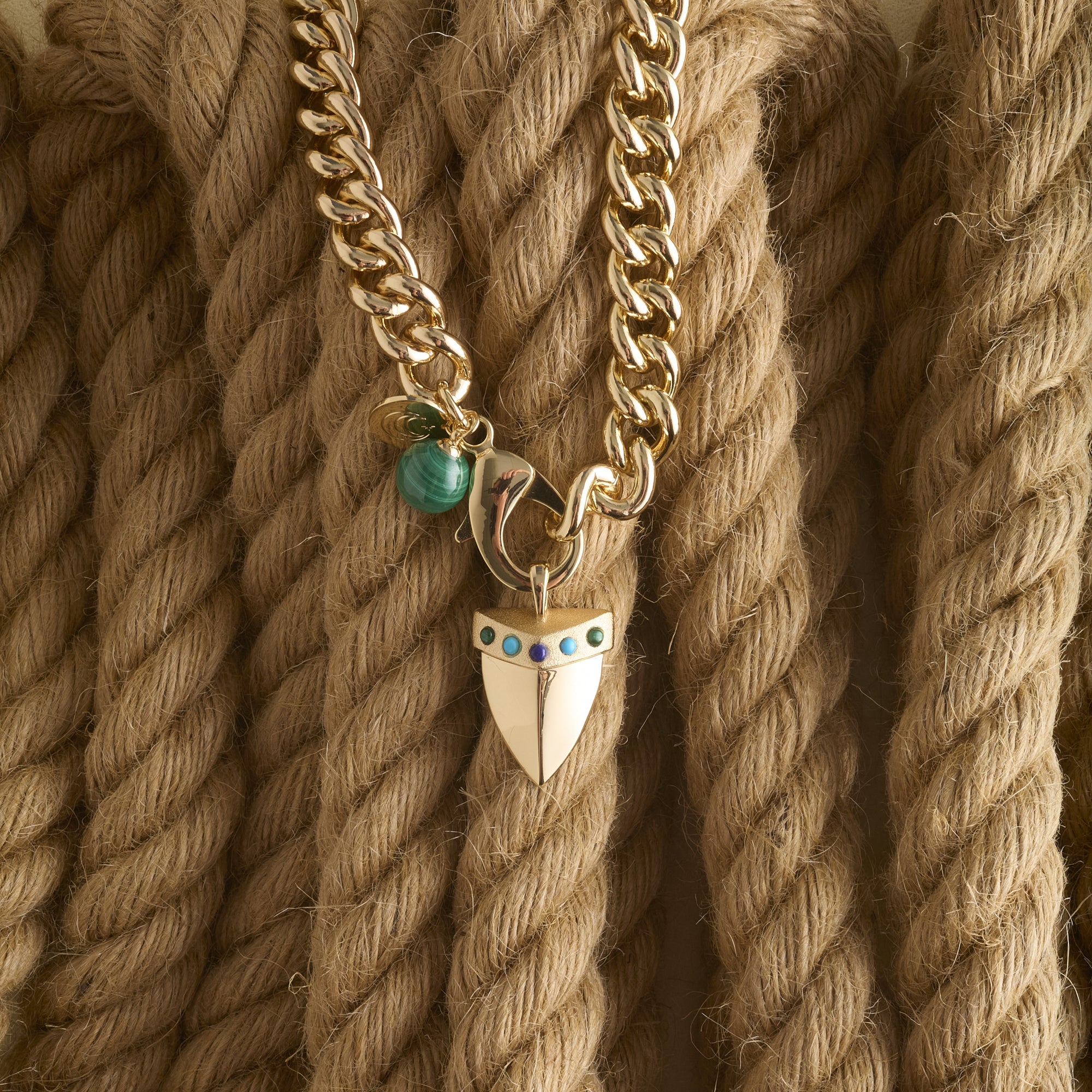 Stylized shot of shark tooth pendant on the curb chain on a pile of ropes