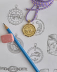 Stylized shot of gold tiger coin pendant on a page of sketches of coin designs