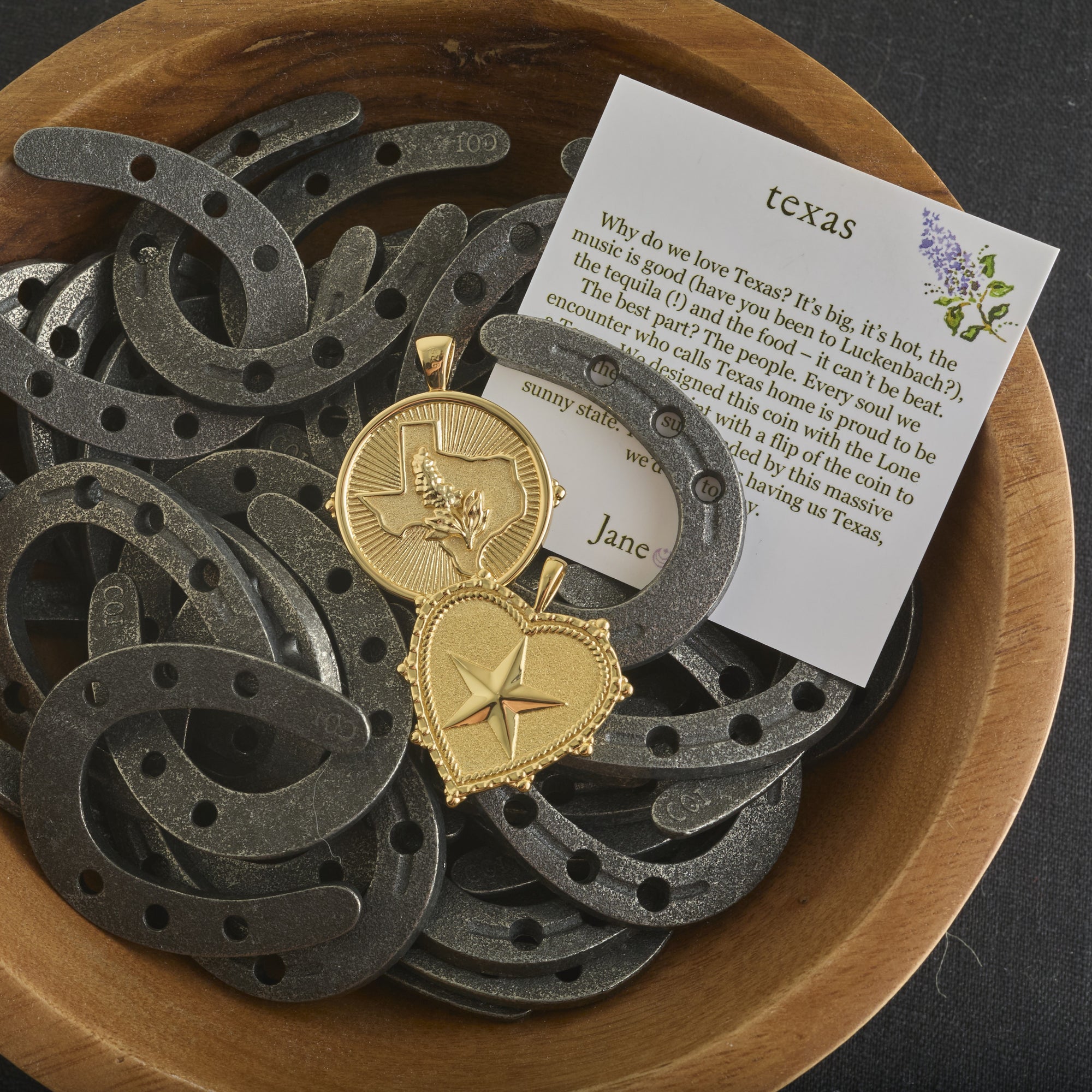 Stylized shot of texas coin and texas heart in a wooden bowl full of mini horseshoes