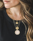 Model wearing layered gold necklaces