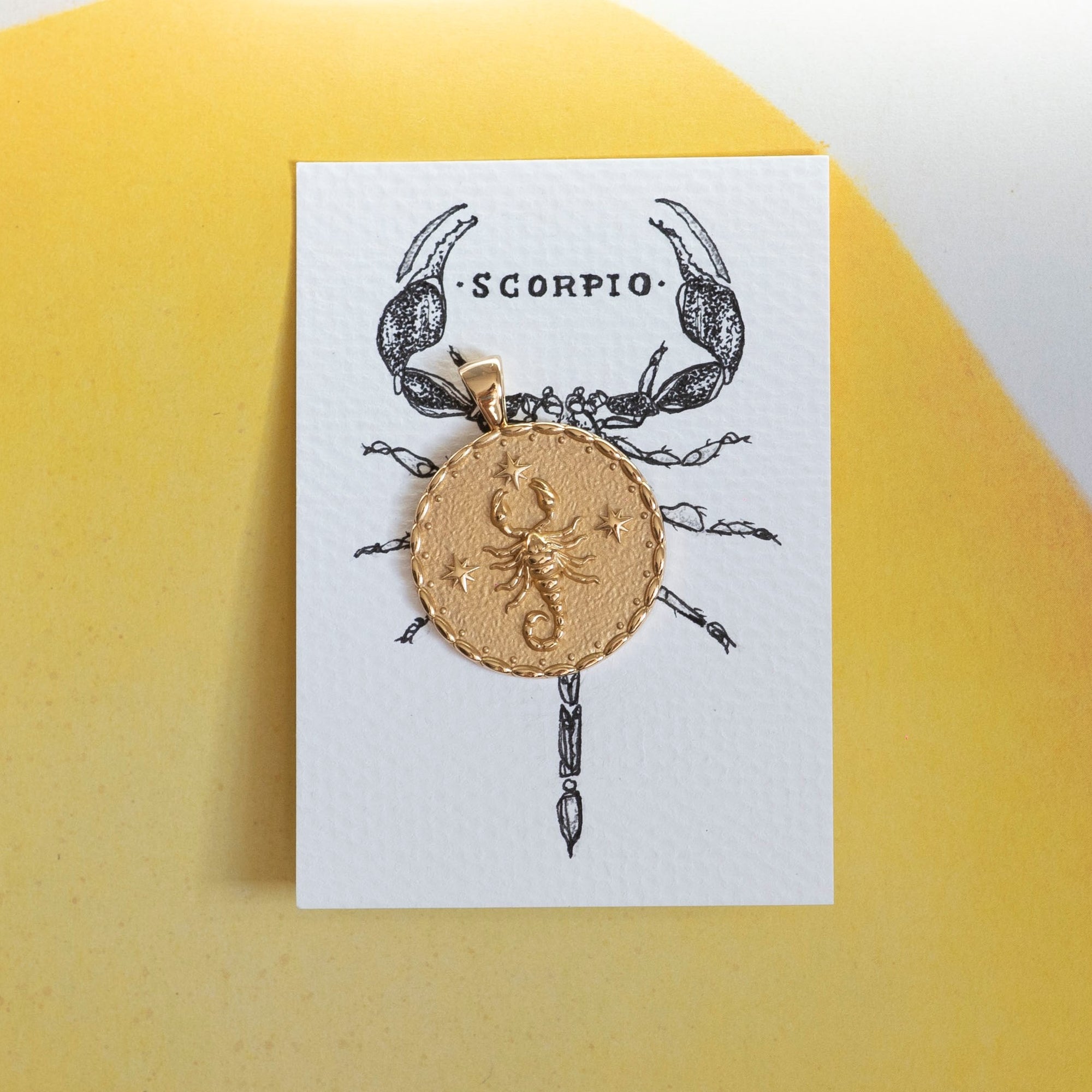 Gold original Scorpio coin pendant on an ink drawing of a scorpion