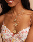 Layered gold necklaces featuring engraved heart coin pendant
