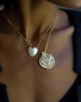 Model wearing layered gold necklaces