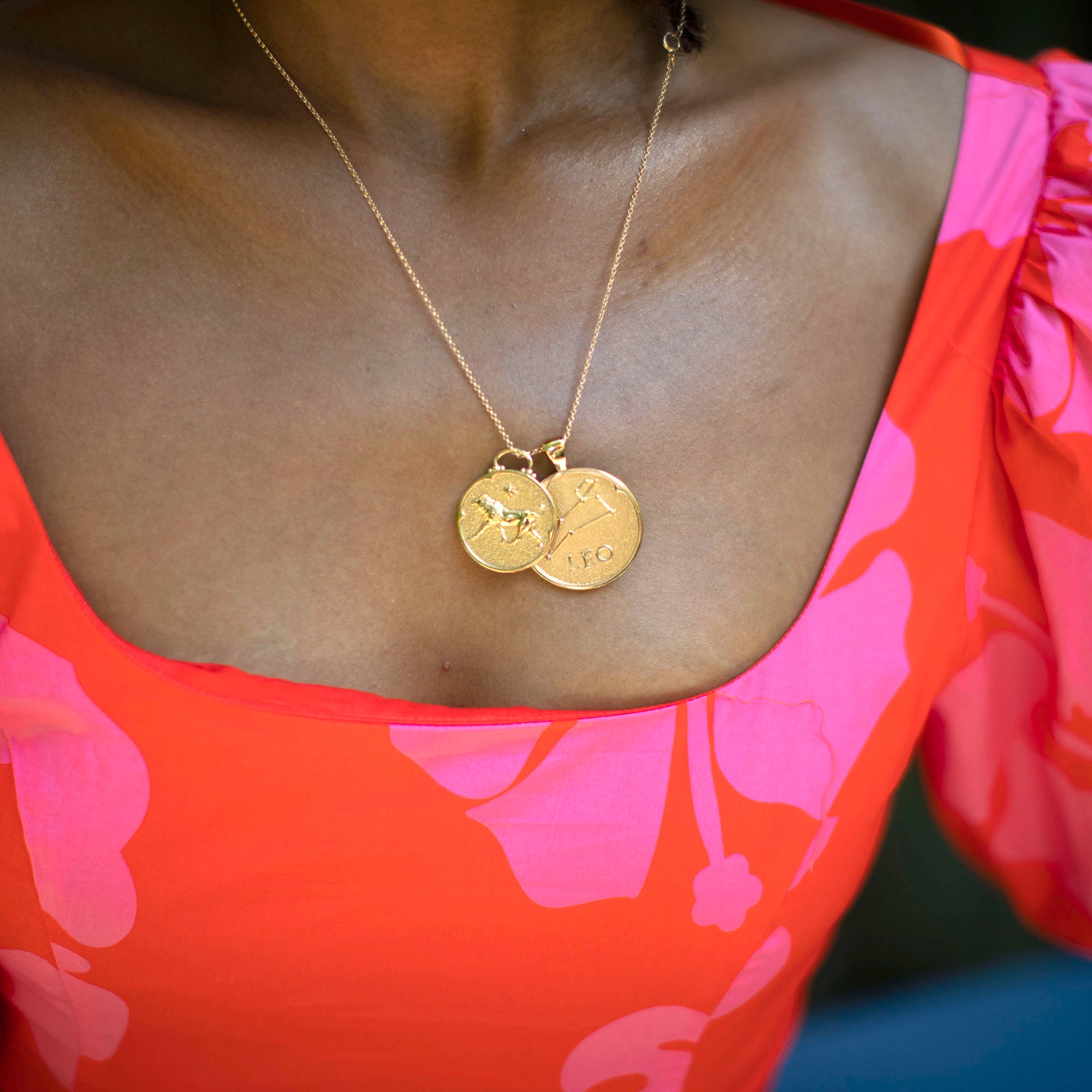 Model wearing gold original and small size Leo pendants on a gold chain