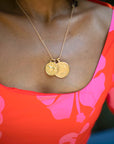Model wearing gold original and small size Leo pendants on a gold chain